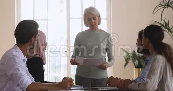 年长的女领导在小组简报会上介绍新的营销计划视频的预览图