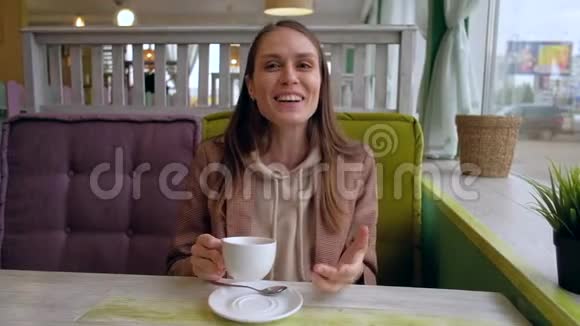 女性坐在咖啡馆里和镜头交谈从同伴的POV拍摄视频的预览图