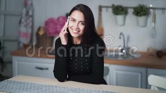 年轻的美女晚上坐在厨房里打电话视频的预览图