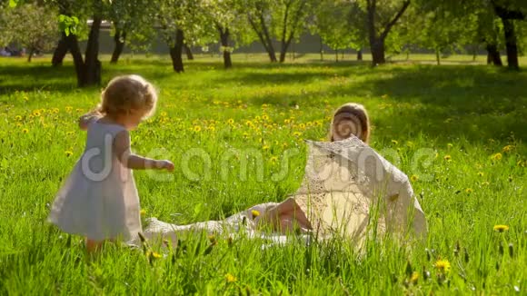 女孩们在阳光明媚的花园里的草坪上玩耍视频的预览图