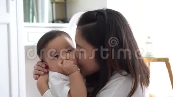 亚洲年轻的母亲在客厅亲吻快乐的儿子视频的预览图