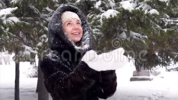 幸福的微笑美丽的女人在她的毛皮白色手套中捕捉雪花视频的预览图