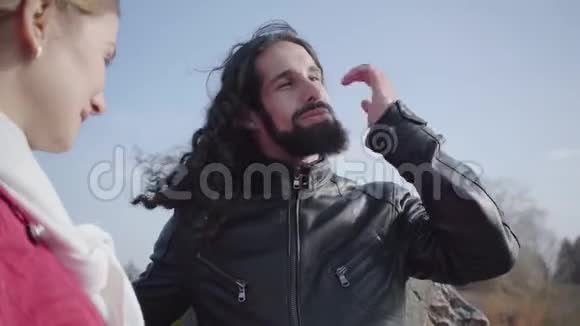 一个留着胡子的中东年轻人站在秋天的公园里和他的白种人聊天视频的预览图