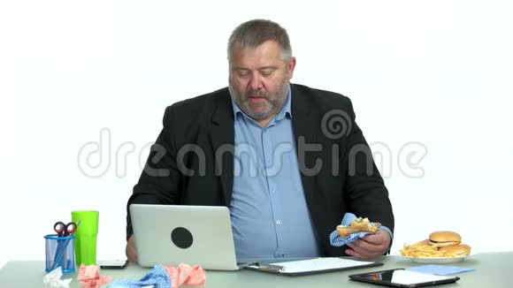 坐在办公室桌面上享受汉堡的商人视频的预览图