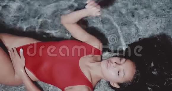 美丽的黑发女人穿着红色泳衣在室外游泳池摆姿势的肖像视频的预览图