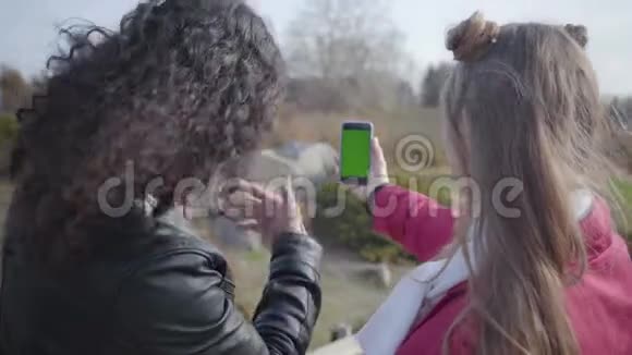 拍到中东青年男子和高加索女子肩扛绿屏智能手机聊天视频的预览图
