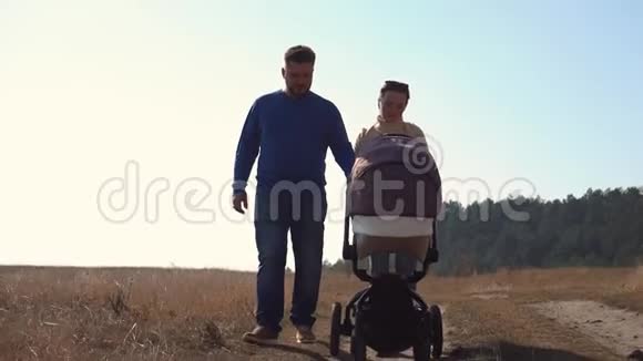 日落时年轻的家庭用轮式婴儿车视频的预览图