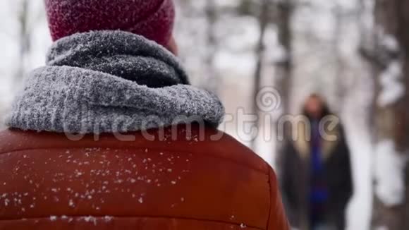 年轻有爱的女人从离经叛道的地方走出来拥抱她的伴侣在下雪的公园里微笑浪漫的情侣享受着雪的享受视频的预览图