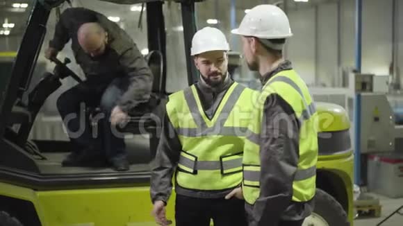 一个留着胡子的白种人从拖车里出来用白盔和绿色迎接他的同事们的画像视频的预览图