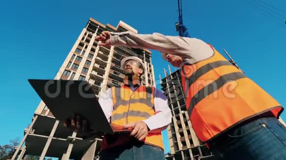 一台笔记本电脑和两栋高层建筑在建的男建筑师视频的预览图