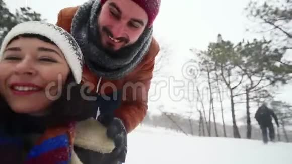 可爱的情侣在冬天滑雪的自拍视频下雪时男人和女朋友推着雪橇女人很开心视频的预览图