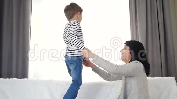 一个快乐的男孩跳上床牵着妈妈或保姆手孩子的情绪幸福的概念视频的预览图
