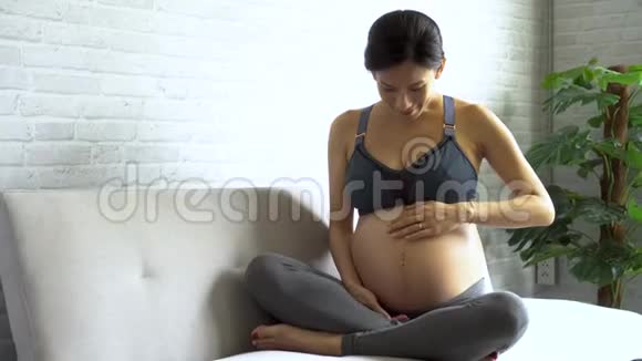 穿着运动服摸肚子的亚洲孕妇视频的预览图