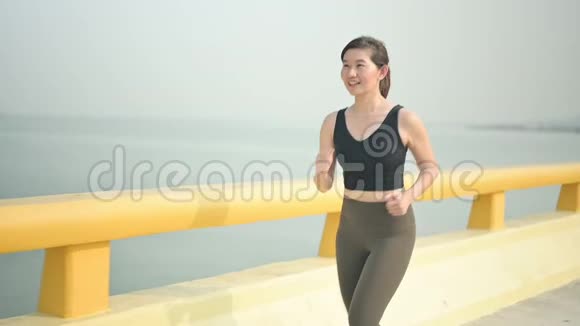 慢动作运动员女子在海滩路跑步视频的预览图