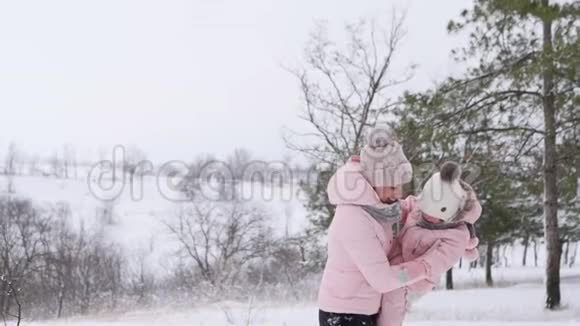 雪天快乐的女人用温暖的连衣裙抱着婴儿微笑妈妈和女儿一起玩视频的预览图
