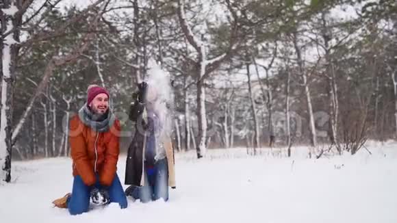 在寒冷的冬天一对快乐的夫妇玩雪把它扔到空中穿着时尚冬装的男人和女人视频的预览图
