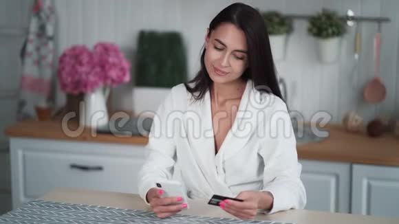 妇女从家里进行网上购买并进入电话信用卡详情视频的预览图