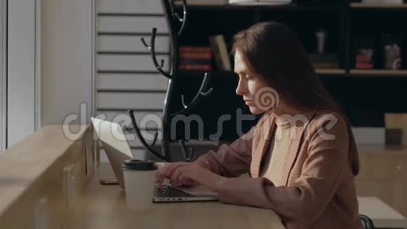 年轻的商务女性穿着西装外套关闭笔记本电脑在咖啡馆喝咖啡视频的预览图