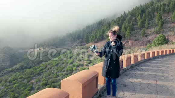 女博主在手机和万向节上拍摄视频内容浓雾笼罩在山中的一片松林中视频的预览图