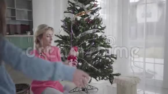 小白种人女孩帮妈妈装饰圣诞树的背面美丽的金发白种人女人和她视频的预览图