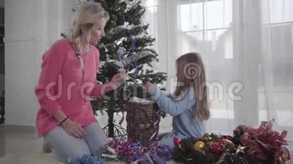 漂亮的白人女人和小女孩说话带着圣诞装饰快乐妈妈帮助女儿选择视频的预览图