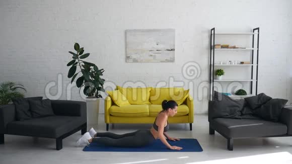 漂亮的年轻女子在房间的地毯上做腹部运动视频的预览图