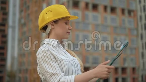 女青年工头将正在建造的建筑物的平面图与实物4K相比较视频的预览图