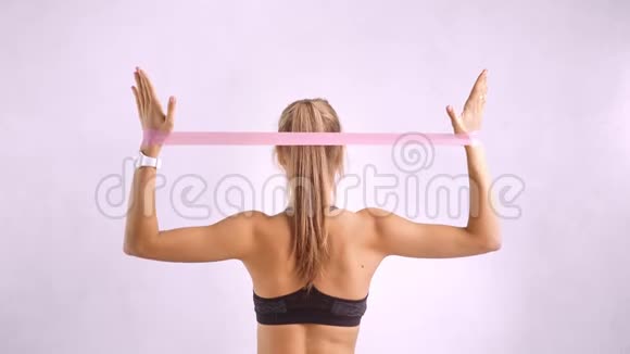 积极健身女性展示背部肌肉锻炼使用橡皮筋后视孤立视频的预览图