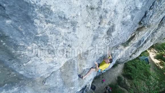 男子攀岩者穿着黄色t恤爬上悬崖寻找到达和抓住户外岩石视频的预览图