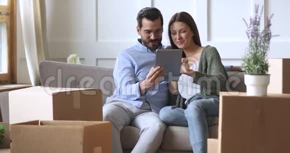 快乐的30岁夫妇在搬家当天使用平板电脑视频的预览图
