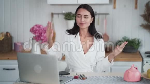 女人在笔记本电脑上听音乐在家里的厨房里跳舞视频的预览图