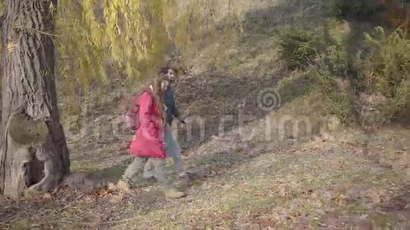积极的年轻两族夫妇带着背包在秋天的森林里散步穿休闲服装的嬉皮士男女视频的预览图