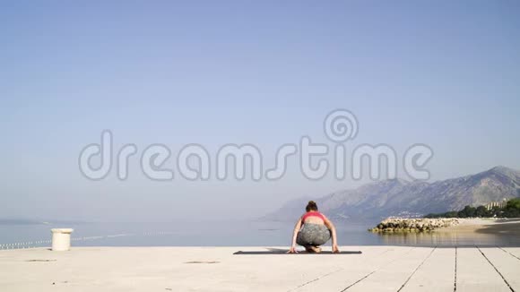 海上码头上坐着莲花的女运动员视频的预览图