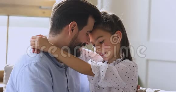 可爱的小女儿抱着爸爸坐在沙发上视频的预览图