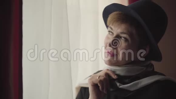 穿着时髦帽子和围巾的体贴的高加索女人的特写脸向窗外望去美丽的肖像视频的预览图