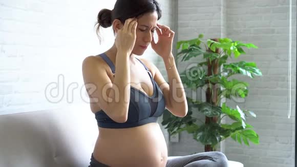 穿着运动服的亚洲孕妇头疼视频的预览图