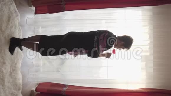 垂直拍摄优雅的白种人黑发女人喝红酒在地板前到天花板窗口优雅优雅视频的预览图