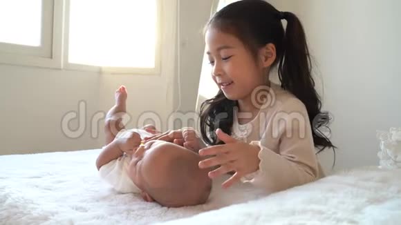 亚洲一家可爱的小妹妹在床上抚摸着刚出生的小男孩弟弟视频的预览图