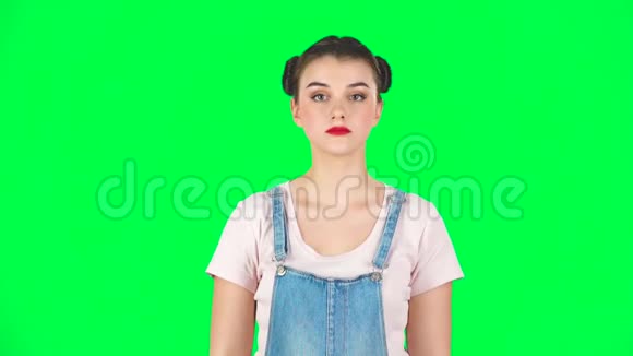 有两个发髻的女人她的嘴唇在绿色屏幕上的红色镜子里慢慢地画着视频的预览图