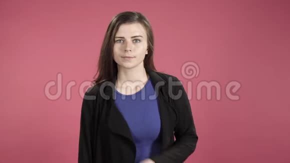 一个年轻严肃的女人在粉红色的背景下双臂交叉在胸前的肖像视频的预览图