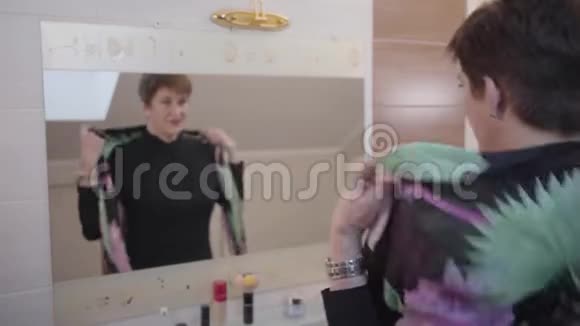 白种人高级女性在大镜子前摆姿势转向相机和微笑的肖像快乐优雅的女士视频的预览图