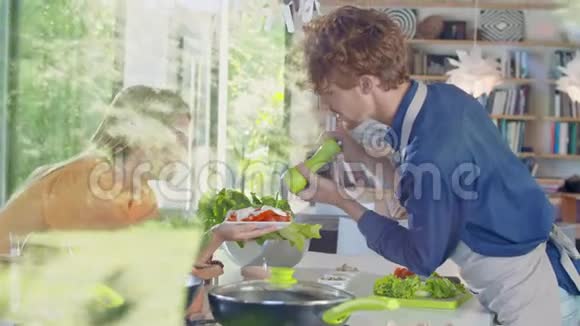 男人把胡椒放在沙拉上年轻人一起做饭准备午餐或晚餐在家中露天厨房视频的预览图