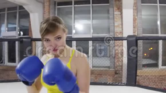 漂亮的女孩穿着黄色T恤拳击手拳击手在笼子里训练视频的预览图