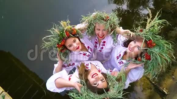 四个穿着花圈和绣花裙子在水中摆姿势的快乐女孩视频的预览图