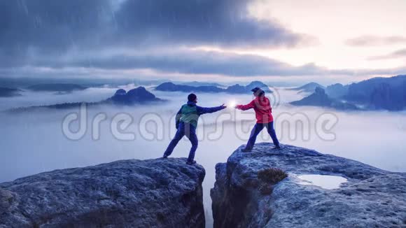 女人向男人展示闪电灯一对夫妇雪日出在山顶上的山谷充满了浓雾视频的预览图