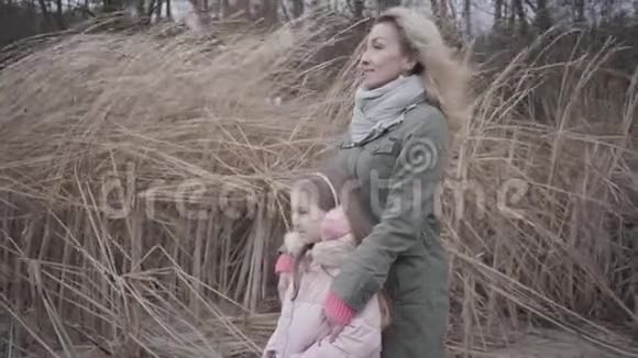 穿着粉红色便服的小白种人女孩和她的母亲站在风中微笑的女人和她的女儿视频的预览图