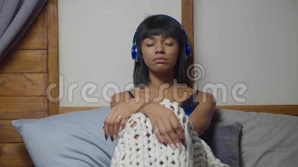 戴耳机的忧郁女人坐在床上视频的预览图