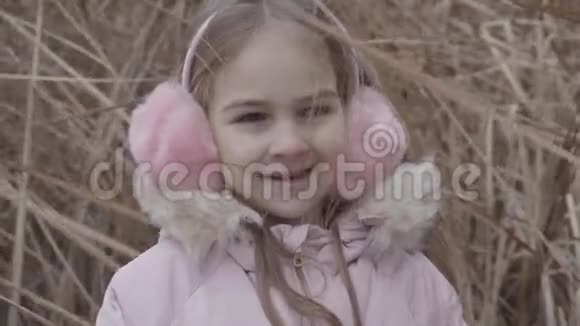 可爱的白种人女孩的特写脸棕色的眼睛看着相机微笑着穿粉色外套的快乐孩子的肖像视频的预览图