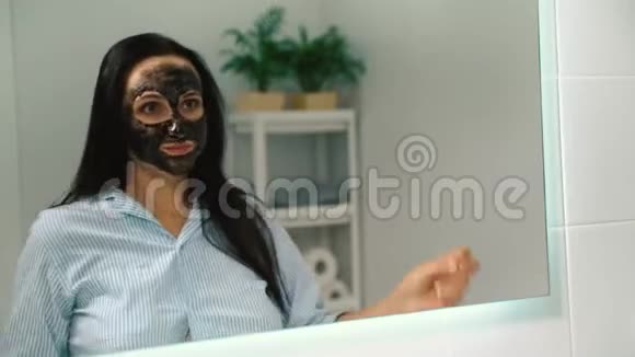 一个年轻快乐的女孩戴着面具在镜子前跳舞视频的预览图