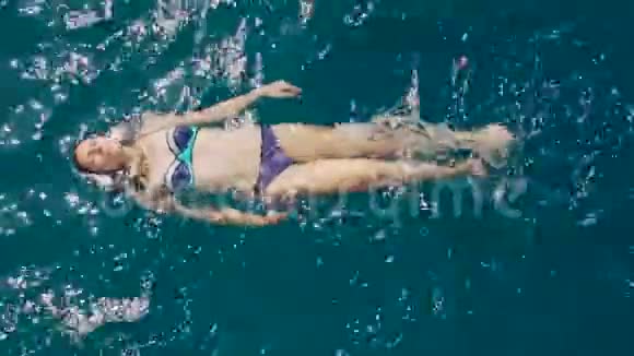 穿着蓝色比基尼的年轻女人在深处游泳视频的预览图